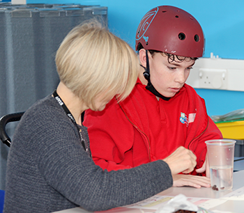Woman helping a boy with global develto read