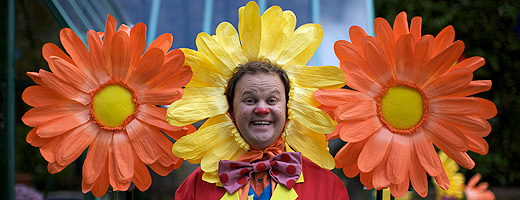 Mr Tumble wearing a very wide orange and yellow flower headdress