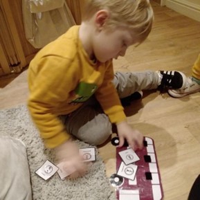 Young boy sitting on floor playing with Makaton Symbol cards