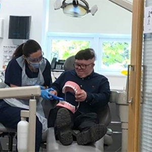 Dentist using a very large set of dentures to explain a procedure to a patient