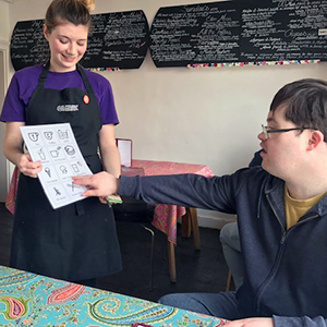 Young man pointing to a symbol menu held by a young waitress
