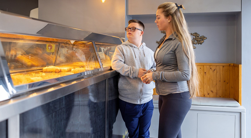 Young man and woman being served in a fish and chip shop