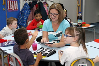 Female teacher interacting with her pupils at a table