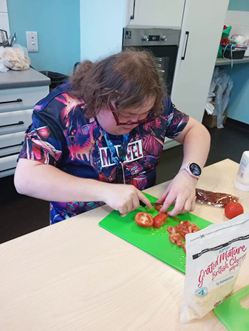 A young woman chopping a tomato