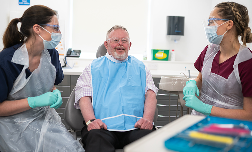 Two female dentistry professionals talk to a male patient